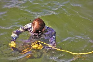 Gespecialiseerde onderwaterlasser voert laswerk uit onder water met professionele apparatuur en veiligheidsuitrusting